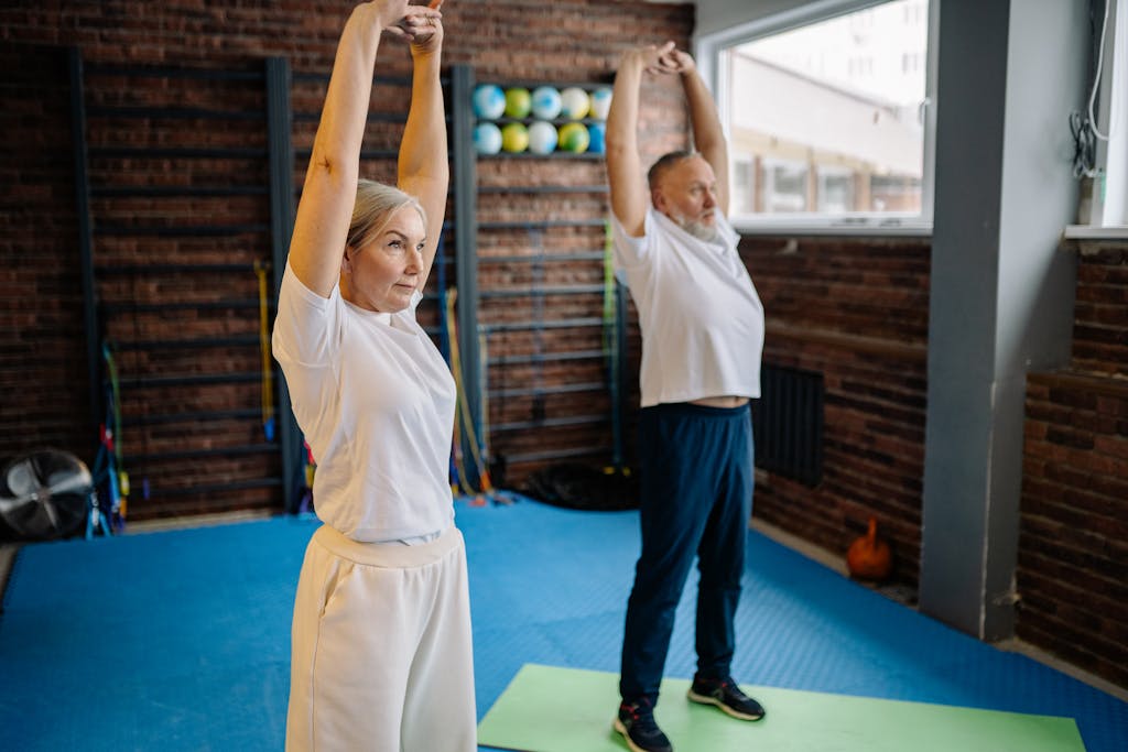 Active senior couple engaging in stretching exercises indoors for fitness and health.